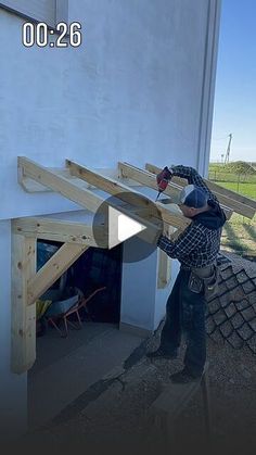 a man working on the side of a building with wooden beams and roofing shingles