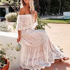 a woman in a white dress sitting on a wall