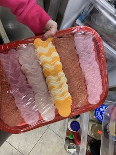 a person holding a tray filled with different types of ice creams and toppings