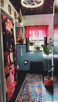 a bathroom with a rug, potted plant and shower curtain on the wall next to it