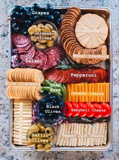 a plastic container filled with different types of cheeses and crackers on top of a table