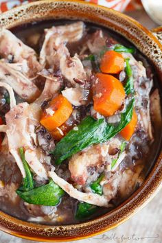 a bowl filled with meat, carrots and spinach