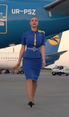 a woman in a blue dress walking towards an airplane