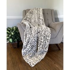 an animal print blanket sitting on top of a chair next to a potted plant