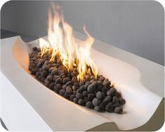 a fire pit with rocks and flames in the center, sitting on top of a white table