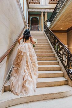 a woman in a wedding dress walking down some stairs