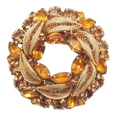 a golden brooch with leaves and stones in it's center, on a white background