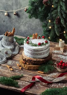 a christmas cake on a wooden table surrounded by greenery and pine cones with red berries