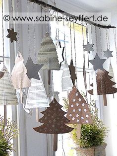 a group of paper christmas trees hanging from a window