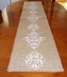 the table runner is made from burlock and jute with white stencils