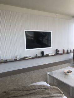 a flat screen tv mounted to the side of a wall above a coffee table in a living room