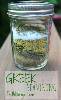 a mason jar filled with green and white seasoning on top of a wooden table