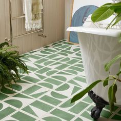 a bathroom with green and white tile flooring next to a bathtub in the corner