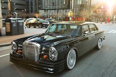 a black car driving down a street next to tall buildings