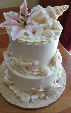 a three tiered cake with seashells and flowers on it