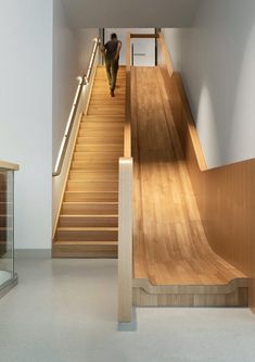 a man walking down a wooden staircase next to a set of stairs with handrails