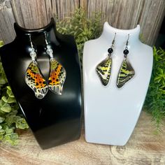 two pieces of jewelry sitting on top of a white display stand next to each other