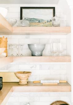 the shelves in this kitchen are filled with dishes and bowls, including one that is empty