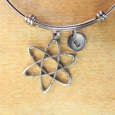 "♥ Silver Atom Charm Bangle Science Teacher Bracelet Atomic Symbol Gift Scientists Biology Researcher Chemistry Gift Personalized Gift ♥ This is a silver-tone Atom charm with hand stamped initial charm on an expandable bangle. ♥ You will receive 1 bangle ♥ Atom Charm 33(12/8\")x26(1\") mm. ♥ Initial charm stainless steel 10mm choose from a drop-down menu. ♥ Bangle 57-64 mm ♥ additional initial https://www.etsy.com/listing/766732811 ♥ We strive for next day shipping, but we do not ship on Saturda Modern Adjustable Nickel Free Charm Bracelet, Modern Adjustable Nickel-free Charm Bracelet, Silver Stainless Steel Friendship Jewelry, Silver Metal Friendship Bracelets, Personalized Silver Metal Bracelets, Modern Adjustable Silver Charm Bracelet, Silver Vintage Jewelry For Friendship, Modern Nickel Free Charm Bracelet, Modern Nickel-free Silver Charm Bracelet