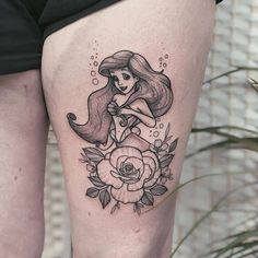 a woman's leg with a tattoo on it that has an image of a mermaid and flowers