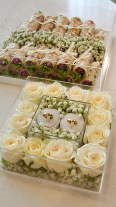 two trays filled with flowers and candles on top of a white tablecloth covered floor