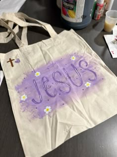 a canvas bag with the word jesus painted on it sitting on a table next to other items