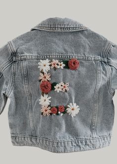 Toddler Jean jacket with floral initial - sizing 18m- youth large  - all items are hand embroidered  - choose the letter and three yarn colors for flowers in personalization box  - please allow for some minor differences as these are all done by hand - jackets fit true to size/ brands will vary depending on availability (typically Old Navy or Target)  - allow up to 3 weeks for item to be made- please message me if you're looking for a rush order Spring Cute Denim Jacket With Pockets, Trendy Spring Outerwear With Letter Embroidery, Cute Embroidered Long Sleeve Denim Jacket, Spring Cotton Outerwear With Floral Applique, Fall Cotton Outerwear With Floral Applique, Casual Cotton Outerwear With Floral Applique, Cute Medium Wash Outerwear For Spring, Cute Medium Wash Denim Jacket For Spring, Cute Fitted Embroidered Outerwear