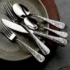 four forks and two spoons on a plate with silverware in the shape of flowers