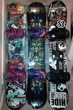 several snowboards are lined up on the floor with stickers all over them and one is upside down