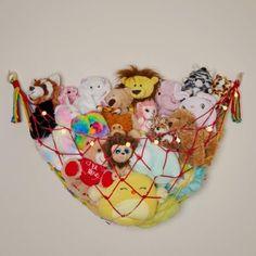 a basket filled with stuffed animals on top of a white wall next to a light