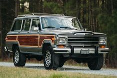 a brown and black truck parked on the side of a road in front of trees