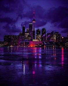 the city skyline is lit up at night with bright lights and reflections on the water