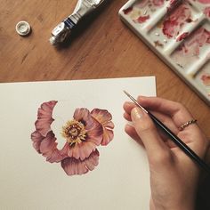 a person is painting flowers with watercolors on paper