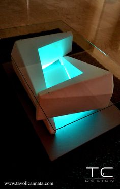 a white couch sitting on top of a floor next to a glass table covered in blue lights