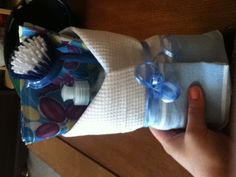 a person holding a bag filled with toothbrushes and soaps on top of a wooden table