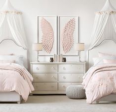 two white beds with pink comforters and pillows in front of them, one has an angel wing design on the headboard