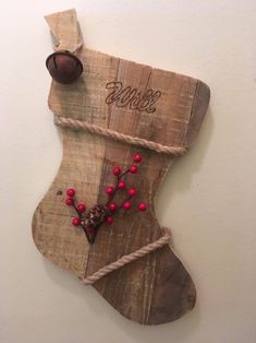 a wooden christmas stocking hanging on the wall with red beads and a pine cone