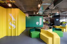 an office with yellow, green and blue furniture in the middle of the floor area