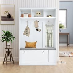 a white coat rack with clothes hanging on it's sides and a yellow pillow sitting on the bench