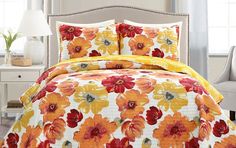 an orange and yellow flowered comforter set on a bed in a room with white furniture