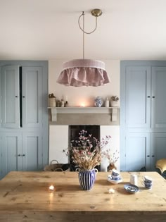 a dining room table with blue cupboards and a large light fixture hanging over it