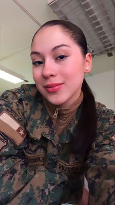 a woman in uniform is smiling at the camera with her hand on her chest and another person behind her