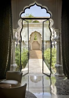 an open doorway leading to a sitting area with white chairs and curtains on either side