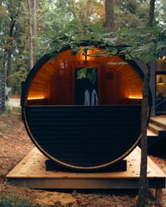 an outdoor sauna in the woods surrounded by trees