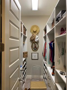 a walk in closet with white shelving and drawers