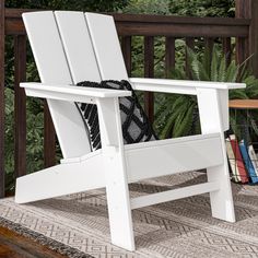 a white chair sitting on top of a wooden deck next to a book shelf and potted plant