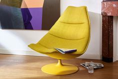 a yellow chair sitting on top of a hard wood floor next to a wall with paintings