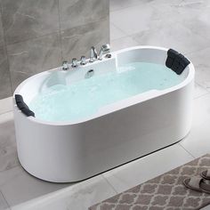 a large white bath tub sitting on top of a bathroom floor next to a rug