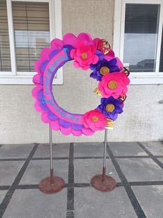 a pink and purple wreath on top of a metal pole next to a building with windows