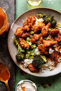 a white plate topped with chicken and broccoli next to a cup of sauce